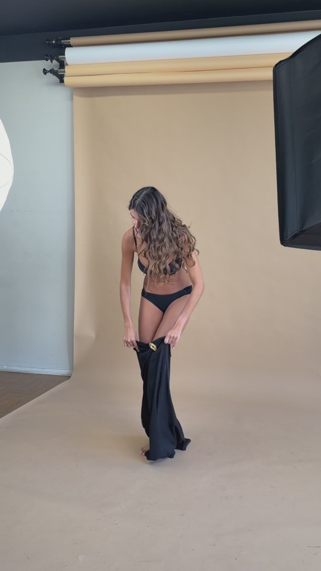 Conjunto Duna Preto em movimento: top com aviamento dourado e saia longa com fenda frontal.