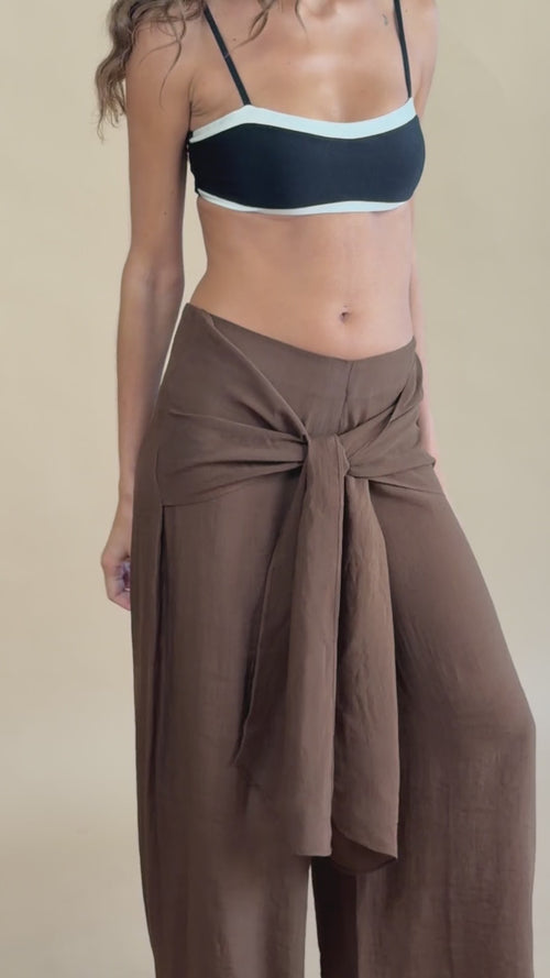 Calça Noronha Marrom em movimento, amarrada na cintura sobre top preto.